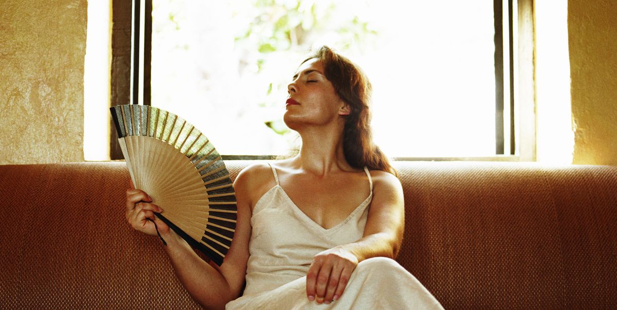 woman holding fan on sofa