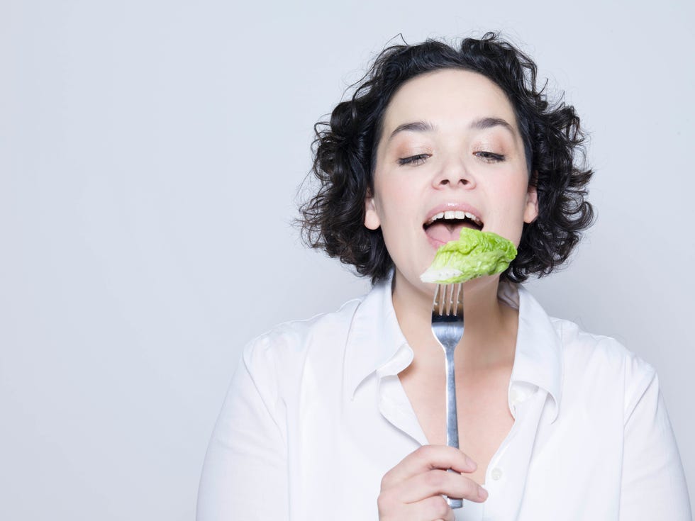 woman holding fork with leaf of salad