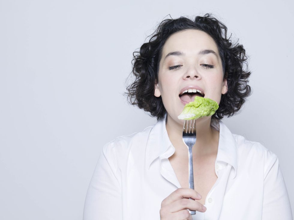 woman holding fork with leaf of salad