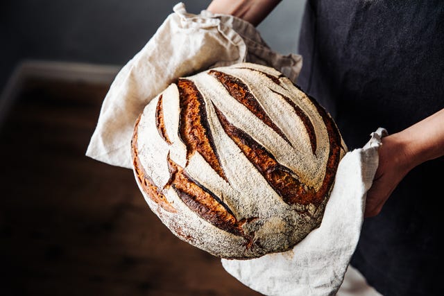 woman holding fresh baked sourdough bread