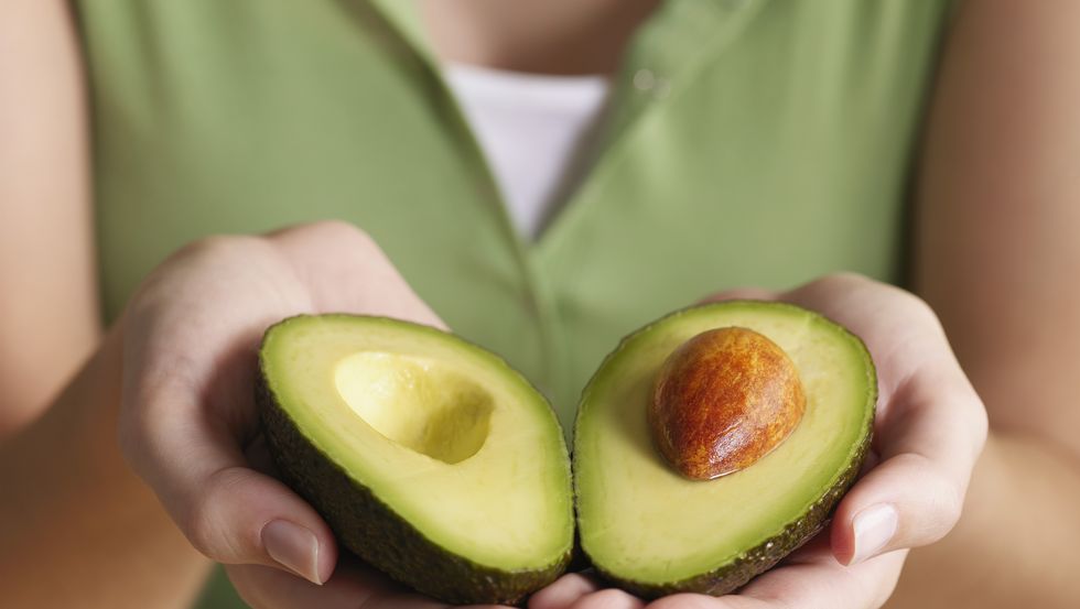 mani che tengono un avocado