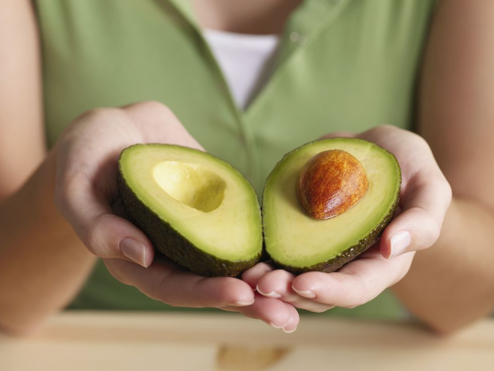 mani che tengono un avocado