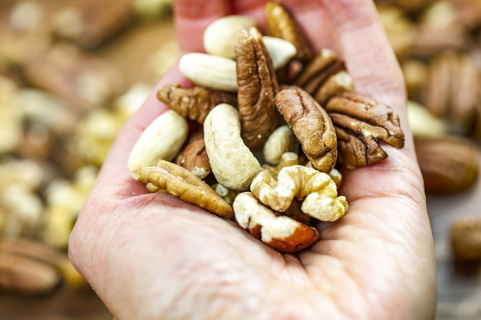woman holding handful of fresh nuts mixed whole nuts nut sources of vitamin b9 folate