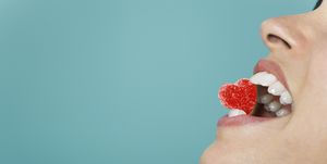 woman holding heart shaped candy between teeth, cropped