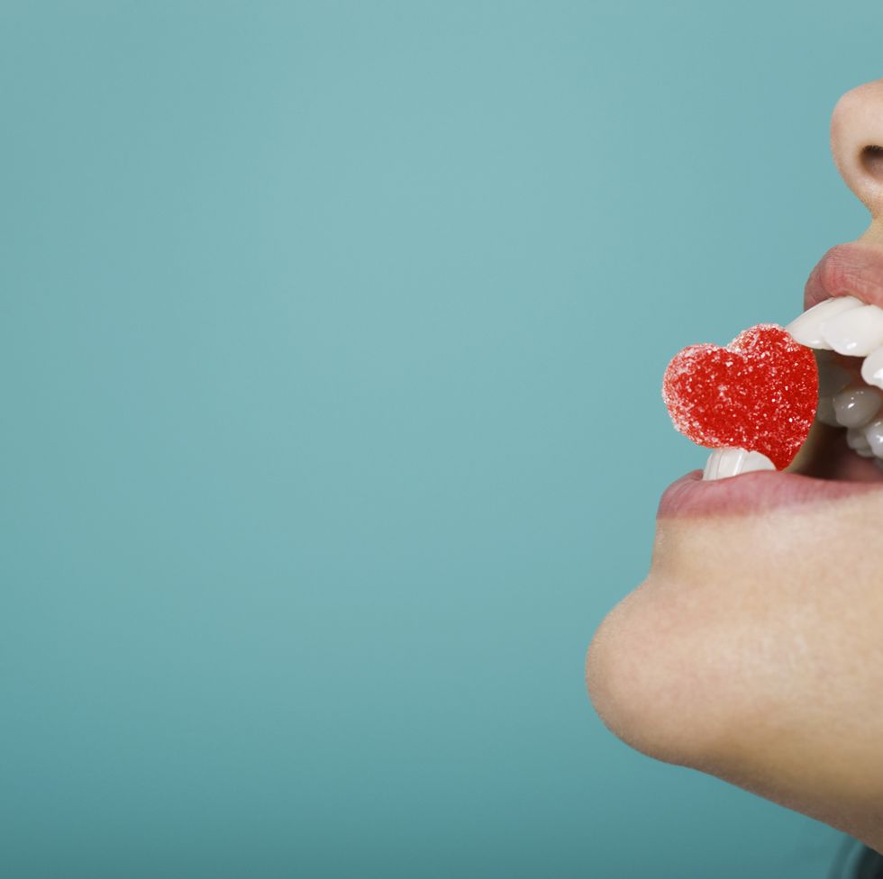 woman holding heart shaped candy between teeth cropped