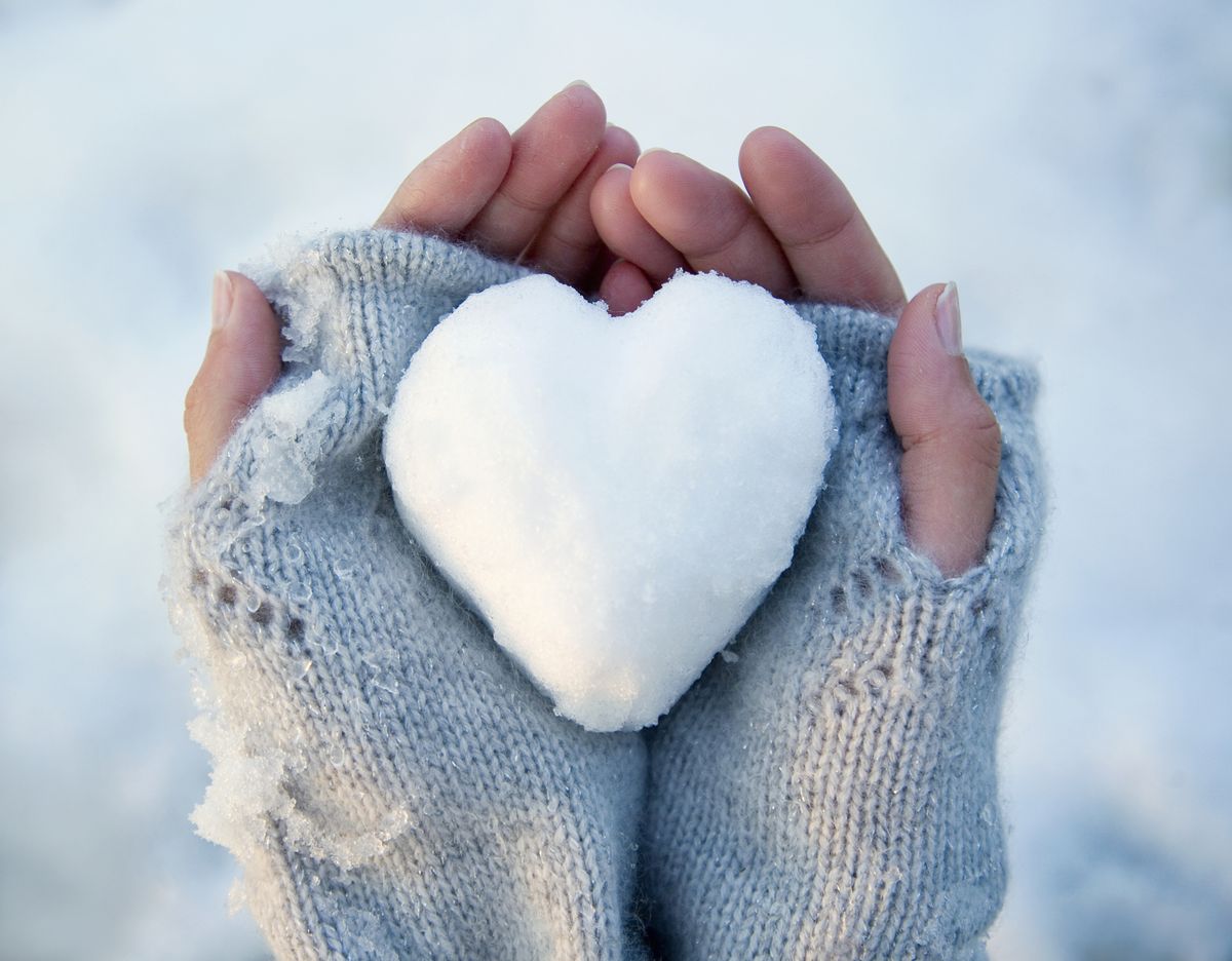 woman holding heart shaped snowball, close up of hands