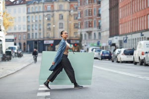 woman holding large shopping bag while walking on street in city