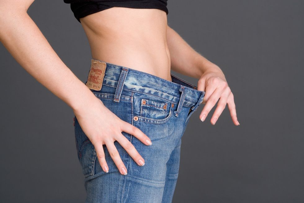 woman holding loose waistband of jeans, mid section