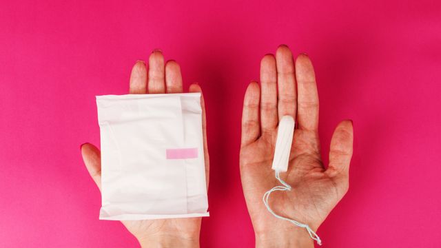 Woman holding menstrual tampon on a pink background. Menstruation time. Hygiene and protection