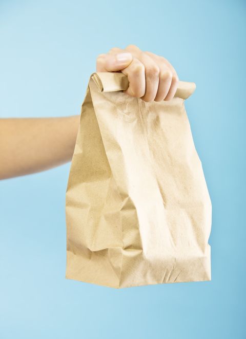 Woman holding packed brown bag lunch