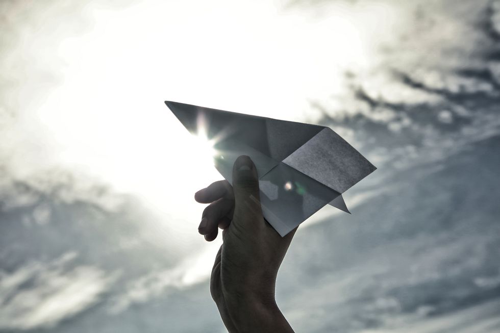 woman holding paper plane toward sky