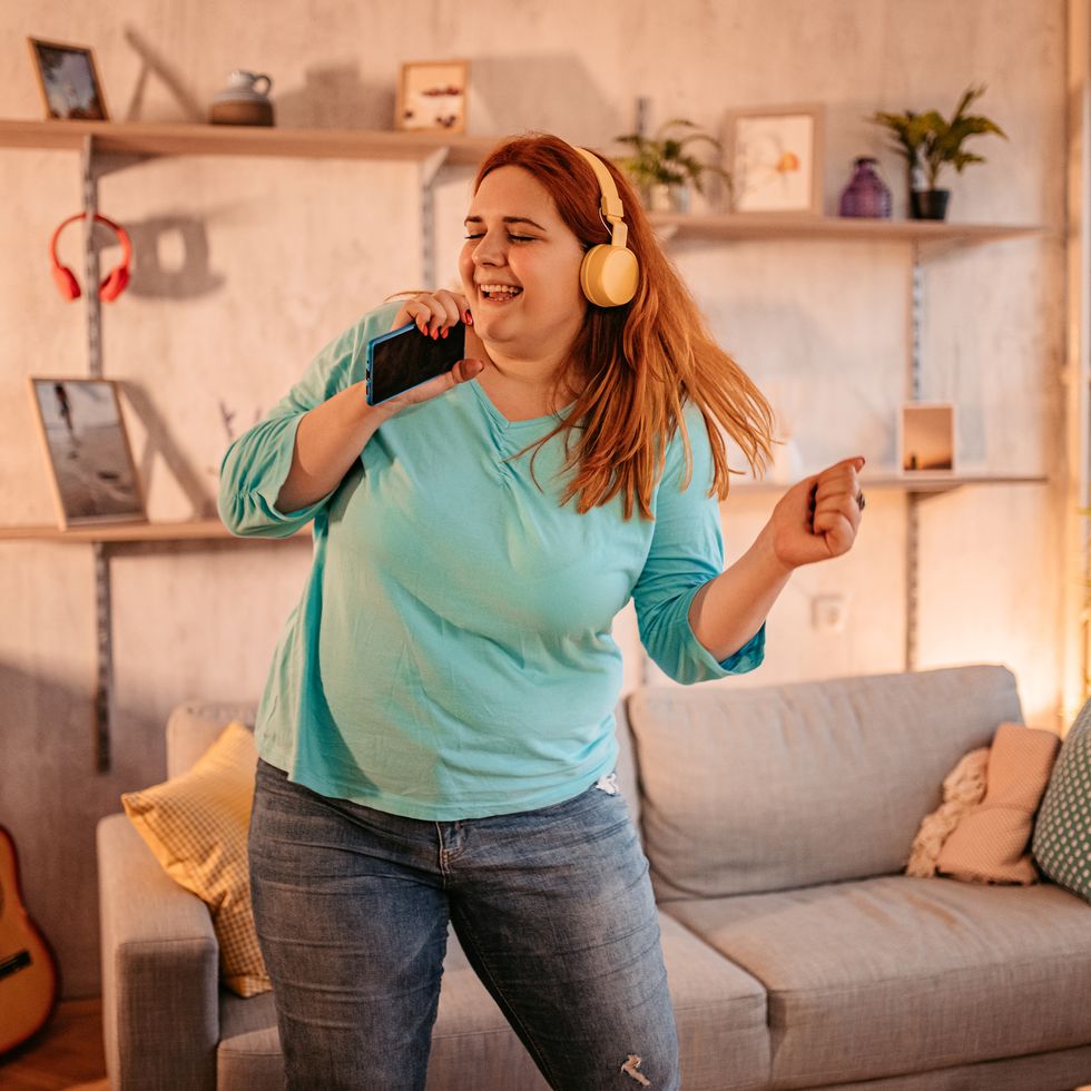 woman holding phone singing and dancing at home