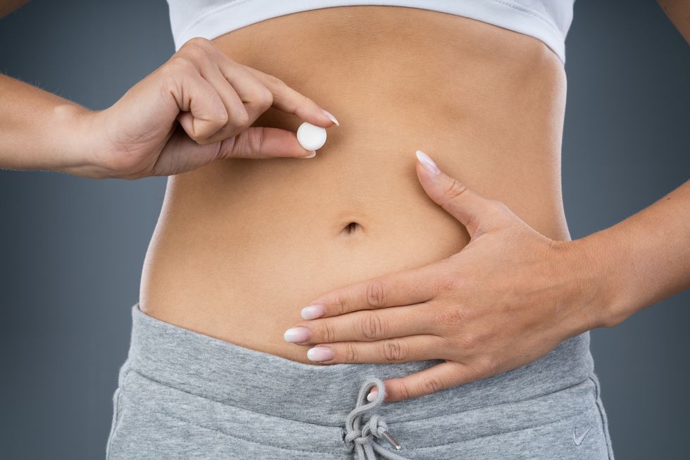 woman holding pill in front of stomach