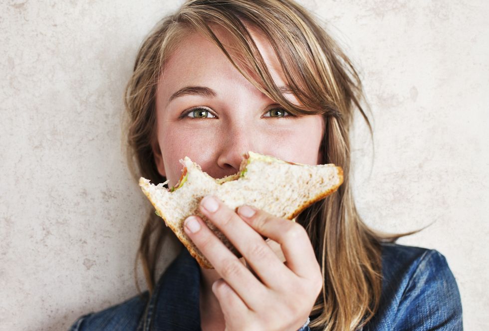 woman holding  sandwich with bites taken from it