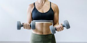 woman holding small dumbbells at gym
