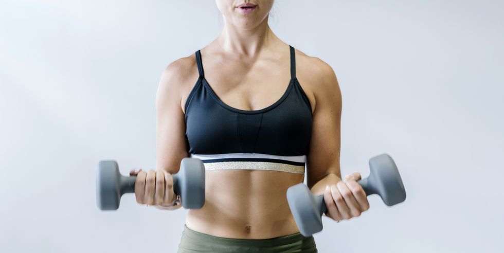 woman holding small dumbbells at gym
