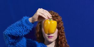 woman holding yellow pepper in front of face