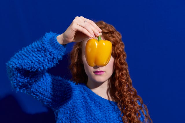 woman holding yellow pepper in front of face