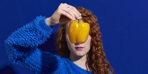 woman holding yellow pepper in front of face