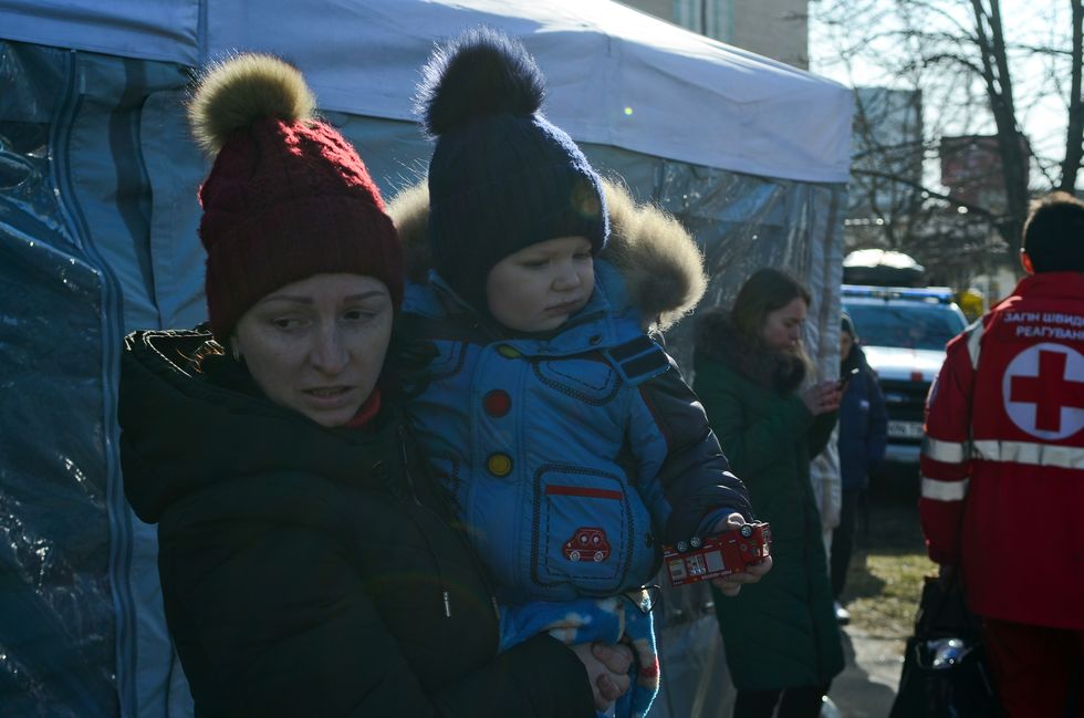 ウクライナの首都、キーウのスヴィアトシンスキー地区でロシア軍が砲撃した結果、住宅の外でおもちゃの消防車を握りしめている男の子を抱く女性。