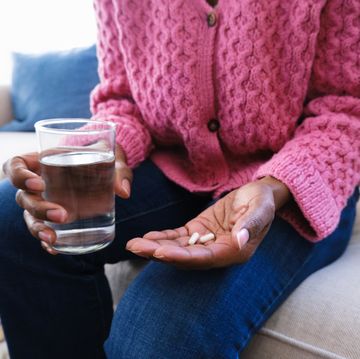 woman holds capsules and glass of water