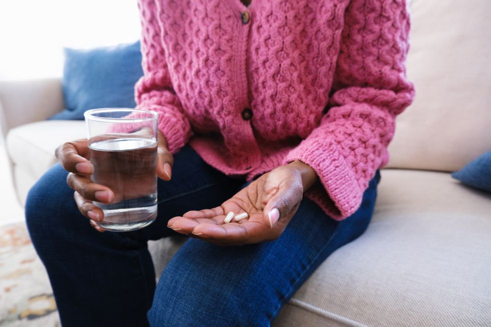 woman holds capsules and glass of water