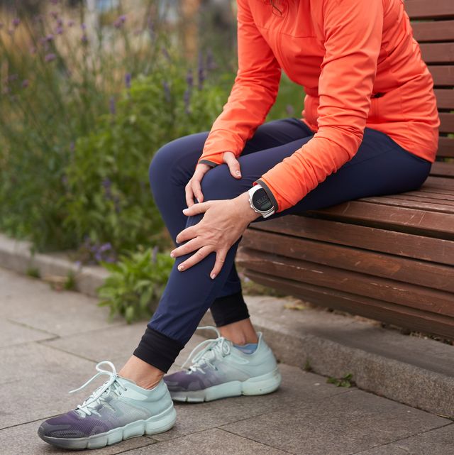 woman holds on to a sore knee after jogging