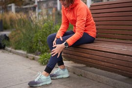 woman holds on to a sore knee after jogging