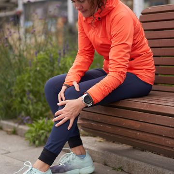 woman holds on to a sore knee after jogging