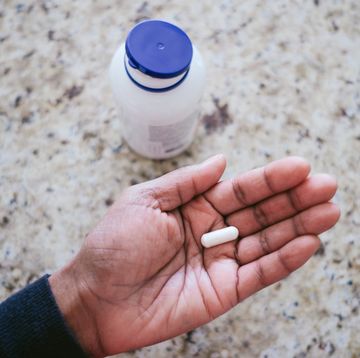 woman holds pill in palm of hand