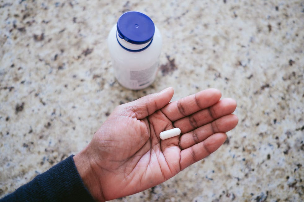 woman holds pill in palm of hand