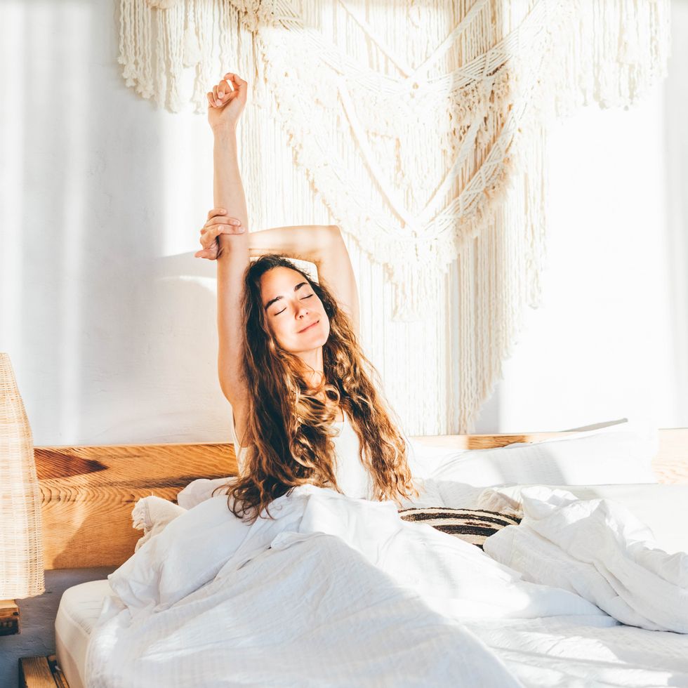woman looking rested waking up in bed on sunny morning