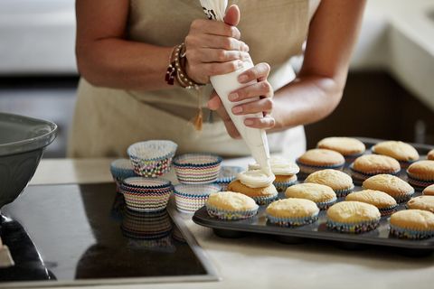 woman icing cupcakes at kitchen counter