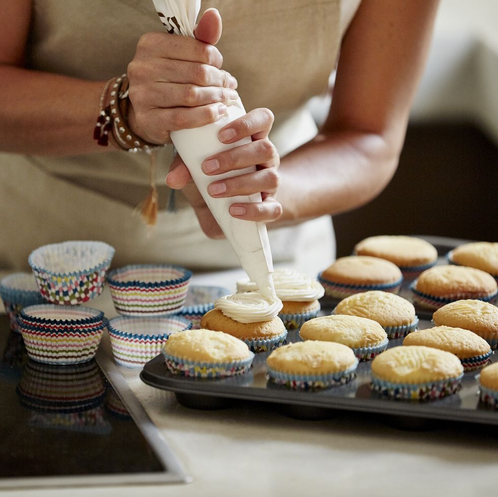 Γυναικεία γλάσο cupcakes στον πάγκο της κουζίνας