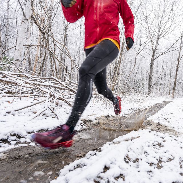 a woman in a red jacket running in mud in winter