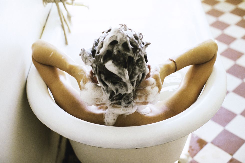 woman in bath shampooing hair