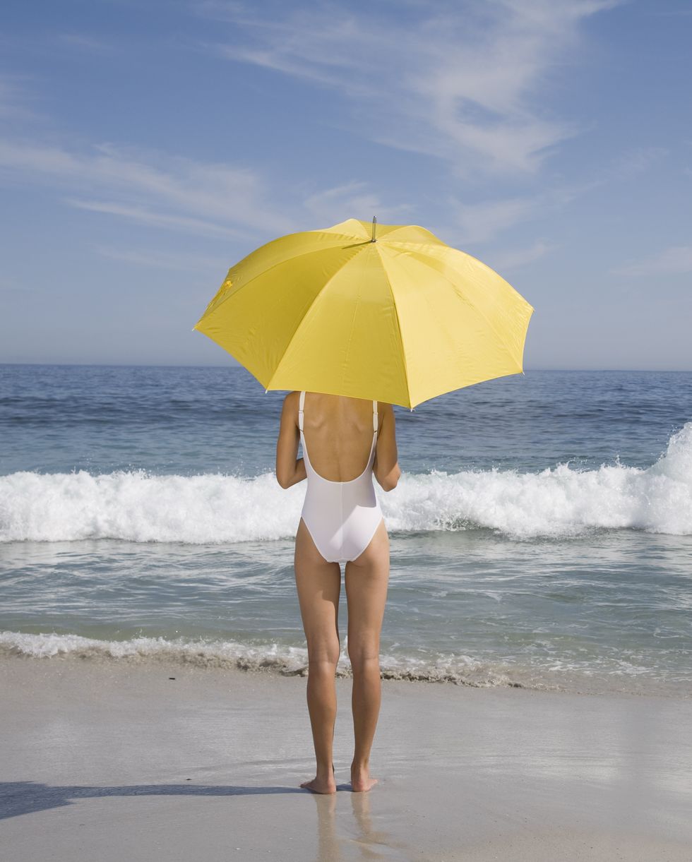 Woman in bathing suit with umbrella on beach