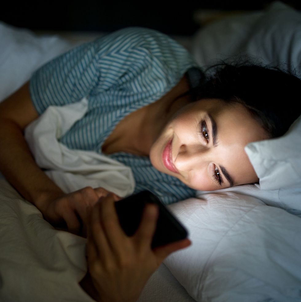 woman in bed checking her mobile phone