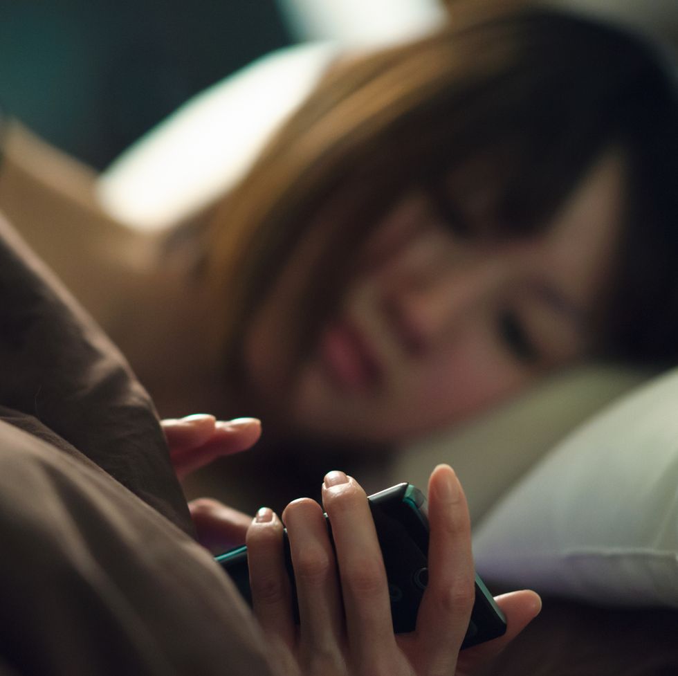 woman in bed reading smartphone