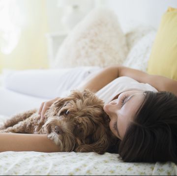 Caucasian woman hugging pet dog in bed