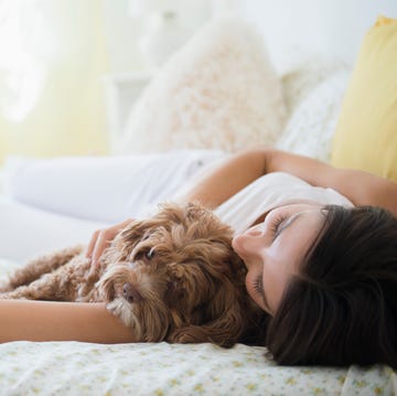 Caucasian woman hugging pet dog in bed