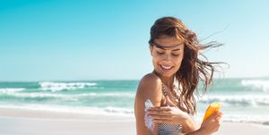 woman in bikini applying sunscreen