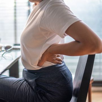 woman in home office suffering from back pain sitting at computer desk