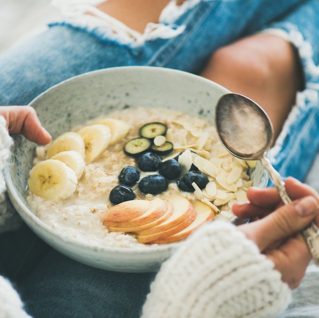 woman in jeans and sweater eating healthy oatmeal porriage