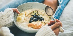 woman in jeans and sweater eating healthy oatmeal porriage