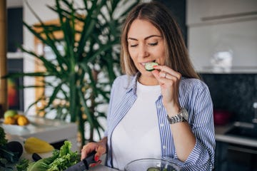 vrouw in de keuken eet komkommer uit tiktok komkommersalade