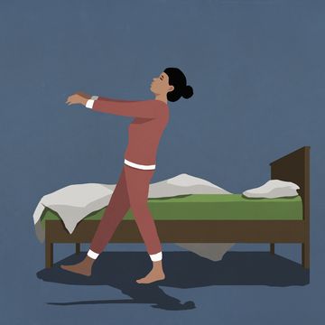 woman in pajamas sleepwalking along bed in nighttime bedroom