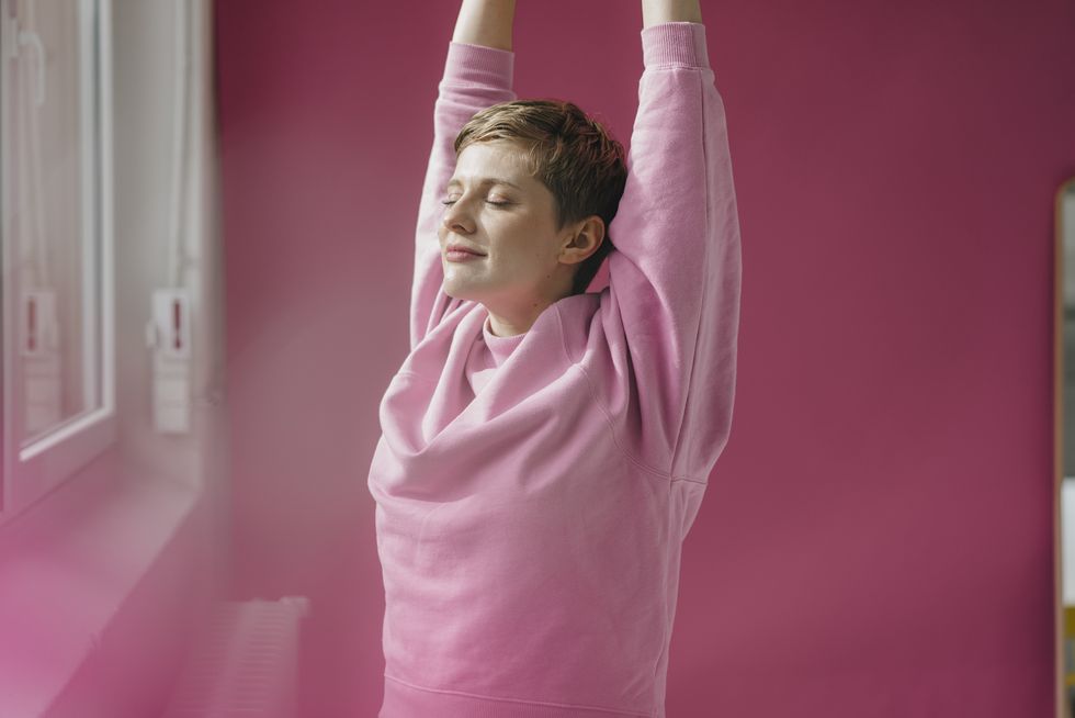 woman in pink stretching at the window