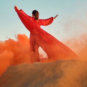 woman in red dress dancing in the desert at blue sky
