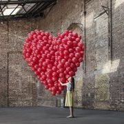 woman in warehouse with heart made of balloons